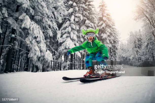 kleiner junge, der an einem schönen wintertag schnell fährt - kids ski stock-fotos und bilder
