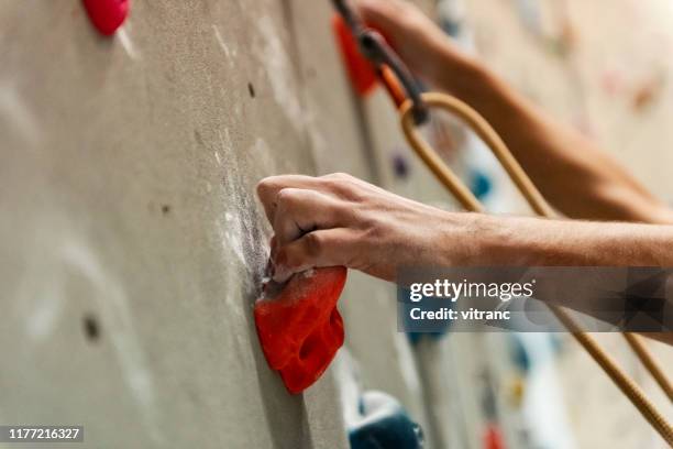 male climber hand gripping hold on climbing wall - climbing wall stock pictures, royalty-free photos & images