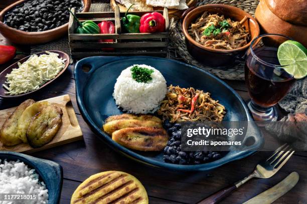 venezuelan traditional food, pabellon criollo with arepas, casabe and papelon with lemon drink - pabellon criollo fotografías e imágenes de stock