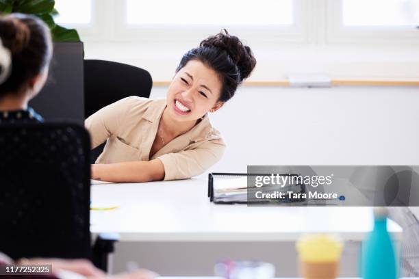 woman grimacing at desk in office - hate palabra en inglés fotografías e imágenes de stock