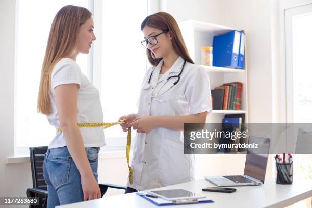 nutritionist measuring bmi of patient in office - nutritionist stock pictures, royalty-free photos & images