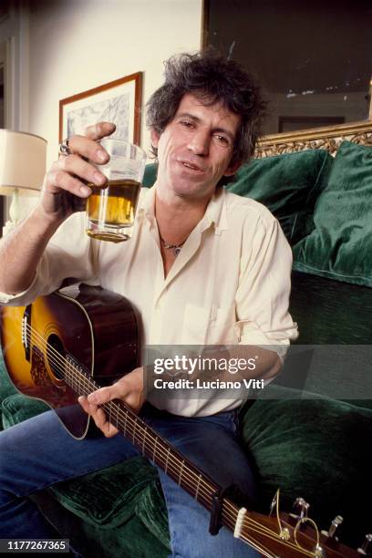 Guitarist of Rolling Stones rock band Keith Richards with a pint of beer and an acoustic guitar, Hotel Excelsior, Rome, Italy, 1984.