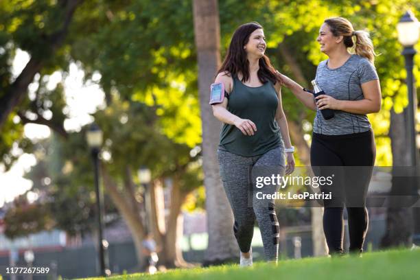 jonge vrouwen joggen en gezond te krijgen in het park - overgewicht stockfoto's en -beelden