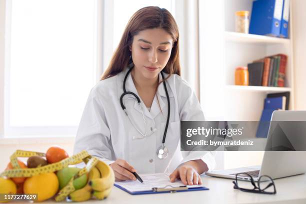 young nutritionist working at desk and writing - nutritionist stock pictures, royalty-free photos & images