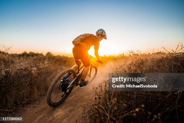 mountian biker riding into the sunset - offroad biking stock-fotos und bilder