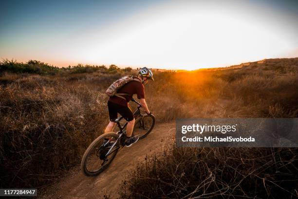 mountian biker riding into the sunset - teenager cycling helmet stock pictures, royalty-free photos & images