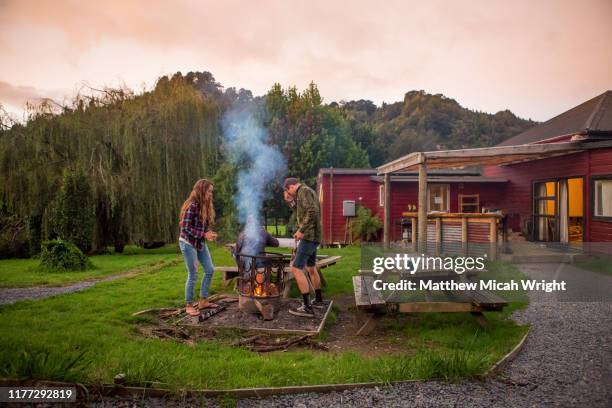 a couple starts a bonfire at the campsite. - lodge foto e immagini stock