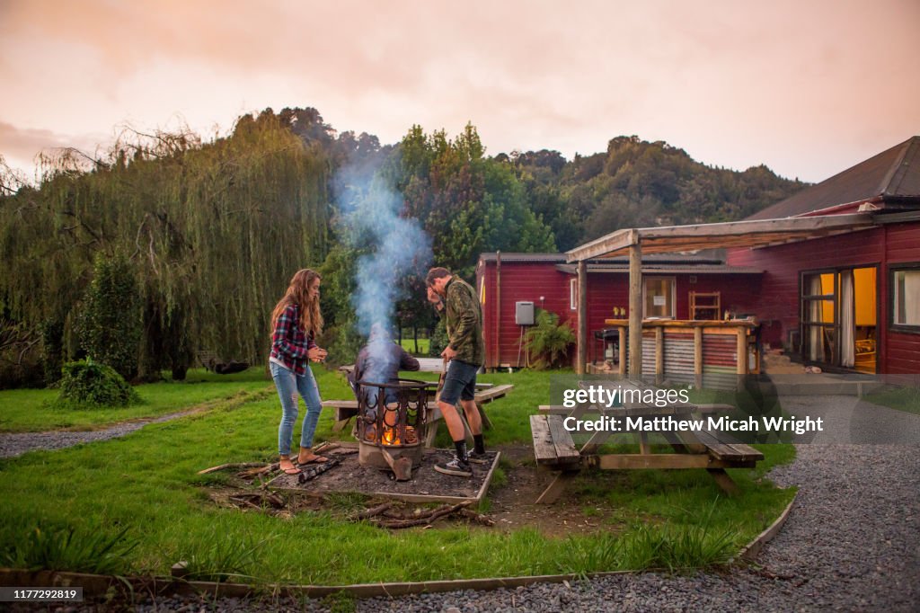 A couple starts a bonfire at the campsite.