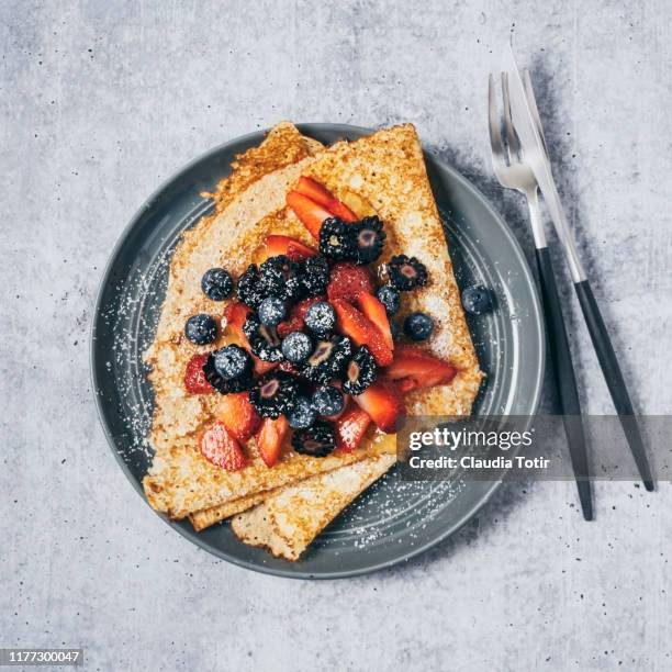 a plate of crepes with berries on gray background - blueberry pancakes stock pictures, royalty-free photos & images