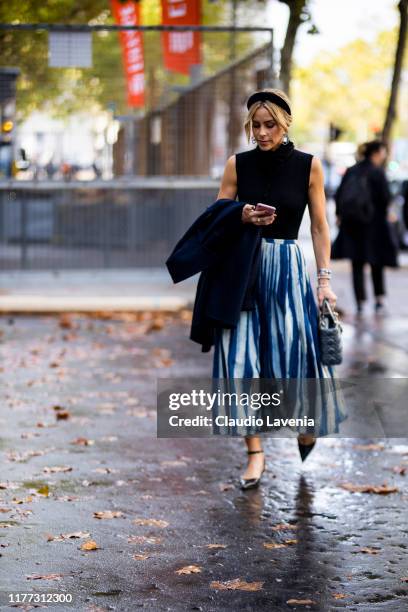Guest, wearing a black top, blue striped skirt, black headband and Dior bag, is seen outside the Faith Connexion show during Paris Fashion Week -...