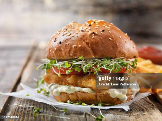 knapperige visburger met tarter saus, sla, tomaat op een briochebroodje - burgers stockfoto's en -beelden