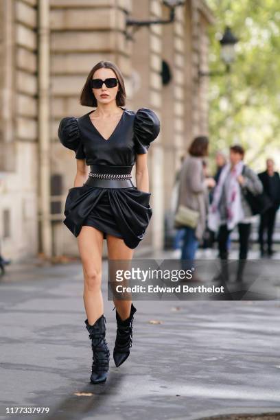 Mary Leest wears sunglasses, a black leather dress with puff shoulder pads and ruffles, black boots, outside Redemption, during Paris Fashion Week -...