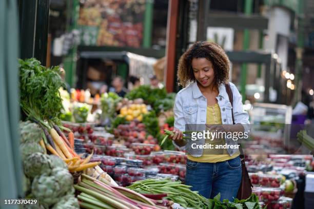 woman buying food at an organic market - mid adult women stock pictures, royalty-free photos & images