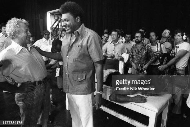 Award winning novelist Norman Mailer jokes with boxing promoter Don King while heavyweight boxer Muhammad Ali lies on the massage table in his...