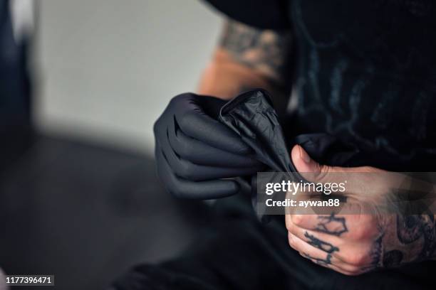 tattoo artist putting on protective gloves - luva de borracha imagens e fotografias de stock