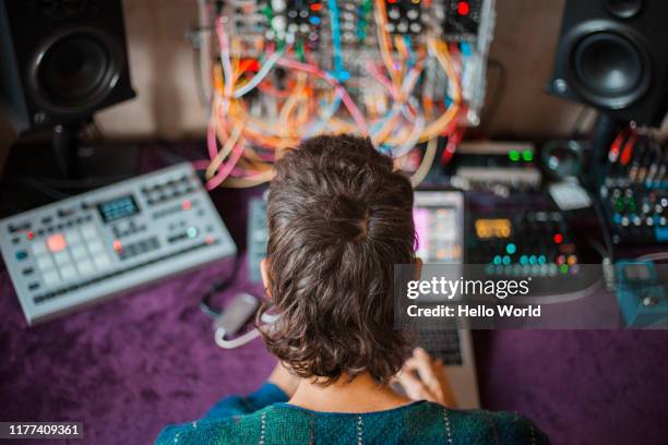 rear view of an electronic music producer in studio mixing sounds - computer cable foto e immagini stock