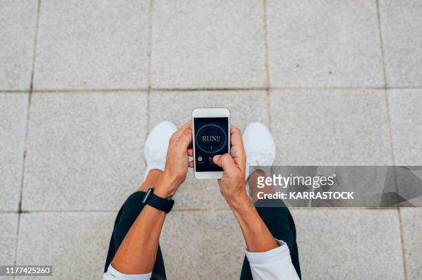 woman runner observes her sport routine on her phone - running gear stock pictures, royalty-free photos & images