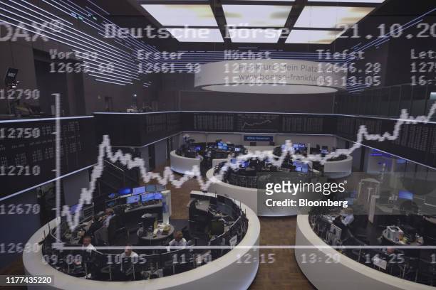 Multiple exposures were combined in camera to produce this image.) The DAX Index curve is displayed over traders working in trading floor pods in a...