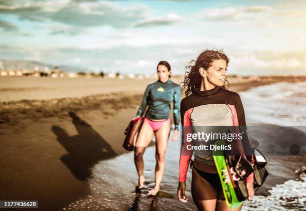 two young women on a beach going kite surfing. - kite surfing stock pictures, royalty-free photos & images