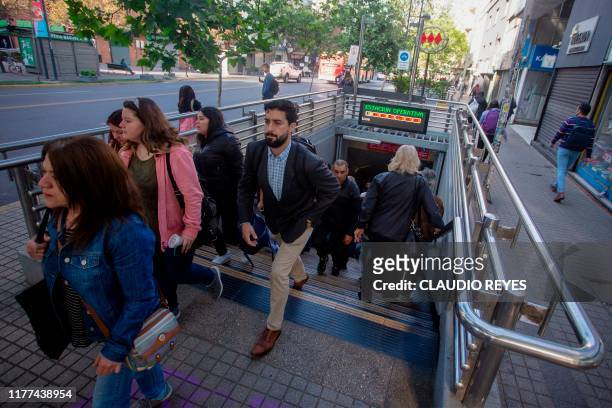 People walk out from the subway station in Santiago, Chile on October 21, 2019. - Santiago's metro opened one of the lines after been closed since...