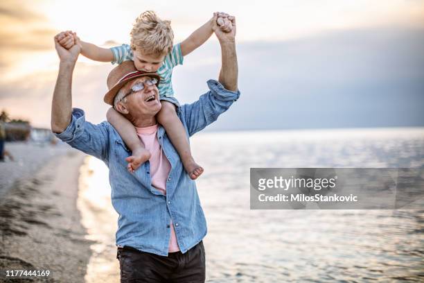 grandfather and grandson at the beach - piggyback stock pictures, royalty-free photos & images