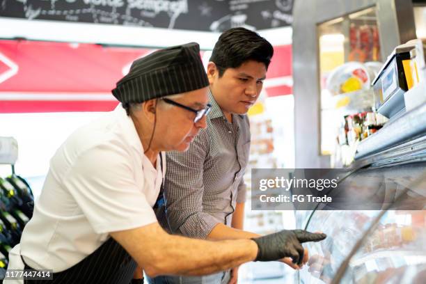 customer choosing products with the support of a butcher in a butchers shop - exhibitor stock pictures, royalty-free photos & images