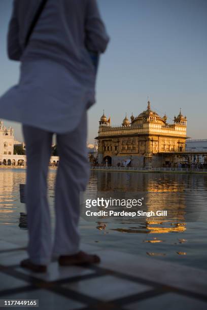 a pilgrim stands at the golden temple (also known as sri harmandir sahib gurdwara) during the vaisakhi festival in amritsar, punjab, india - baisakhi stock pictures, royalty-free photos & images