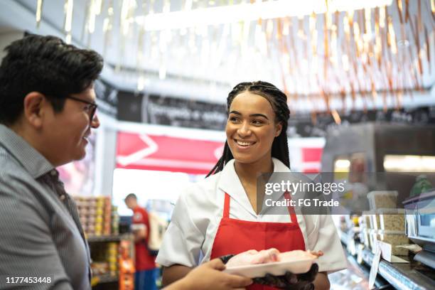 customer choosing products with the support of a butcher in a butchers shop - exhibitor stock pictures, royalty-free photos & images