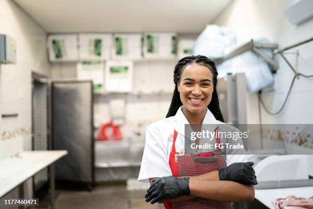 ritratto di macellaio in piedi in una macelleria - butcher foto e immagini stock