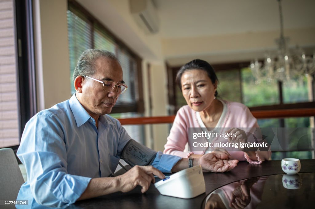 Hombre mayor Comprobar su presión arterial en casa con su esposa