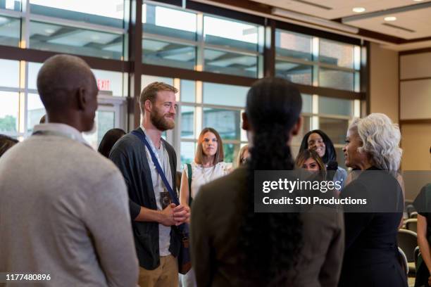 mature conference speaker addresses hipster during q and a - diverse town hall meeting stock pictures, royalty-free photos & images