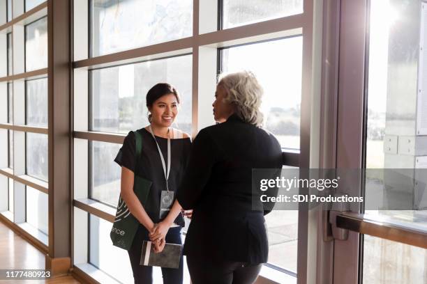 mid adult woman listens eagerly to mature conference speaker - lanyard stock pictures, royalty-free photos & images