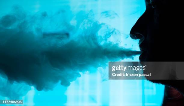 man smokes an electronic cigarette in town . - vape stock pictures, royalty-free photos & images