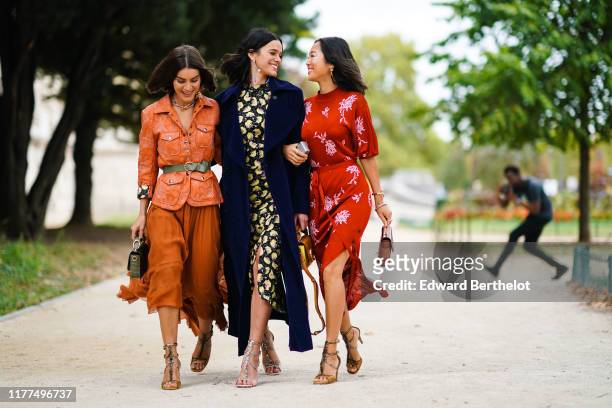 Camila Coelho wears earrings, a necklace, an orange quilted safari jacket, an almond-green belt, an almond-green crocodile pattern Chloe handbag, a...