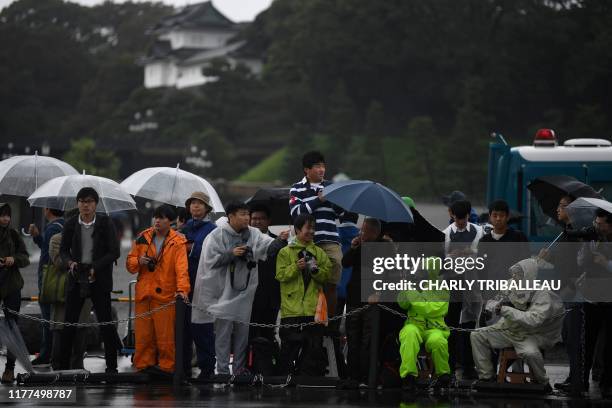 People stand near the Nijubashi gate at the Imperial Palace on the day Japan's Emperor Naruhito will officially proclaim his ascension to the...