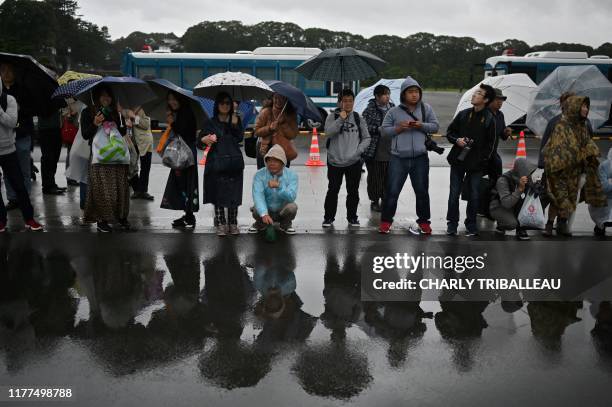 People stand near the Nijubashi gate at the Imperial Palace on the day Japan's Emperor Naruhito will officially proclaim his ascension to the...