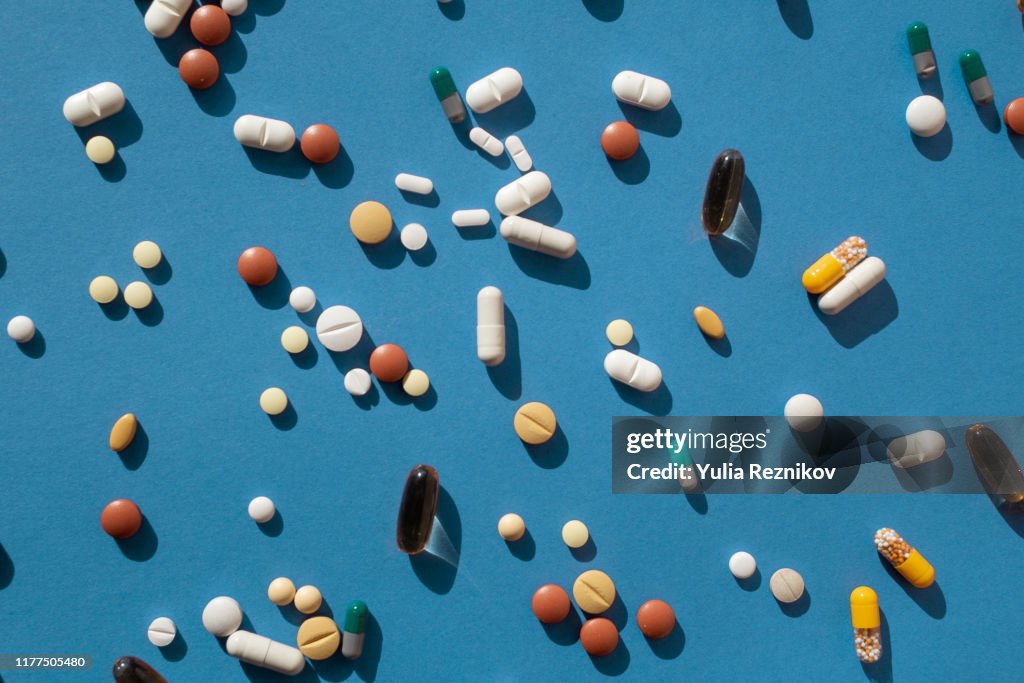 Top view of various pills and tablets on the blue background