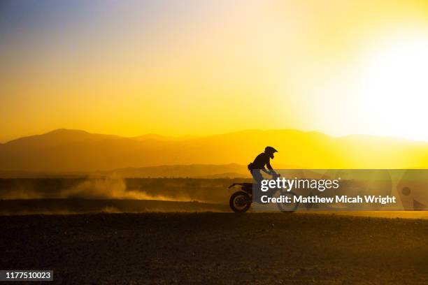 a motorcycle races through the desert. - corrida de motocicleta - fotografias e filmes do acervo