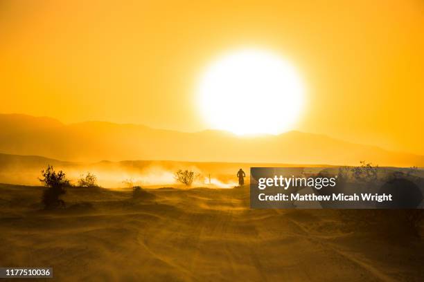 a motorcycle races through the desert. - orange california stock pictures, royalty-free photos & images