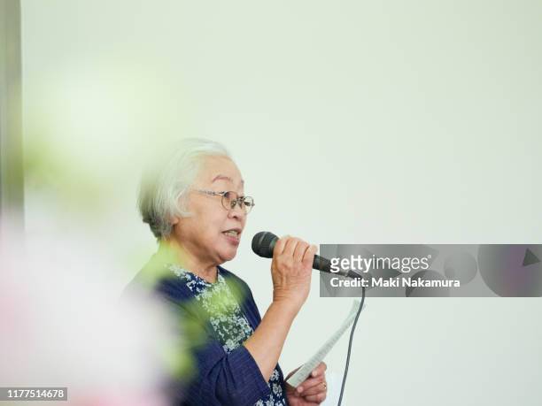 Grey-haired senior woman talking using a microphone