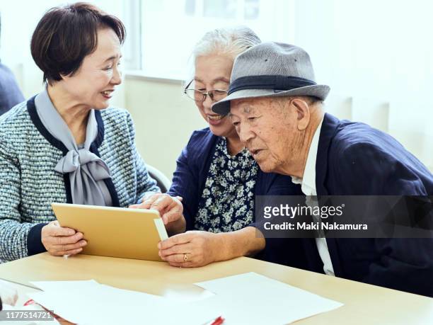 Senior women and men talking happily while looking at tablet computer