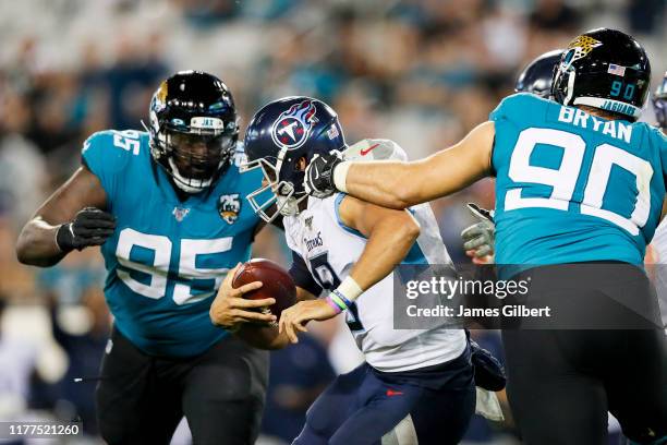 Taven Bryan of the Jacksonville Jaguars and Abry Jones tackle Marcus Mariota of the Tennessee Titans at TIAA Bank Field on September 19, 2019 in...