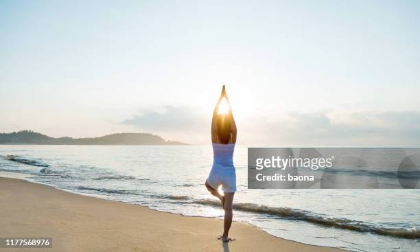 frau, die yoga am strand macht - woman standing exercise stock-fotos und bilder