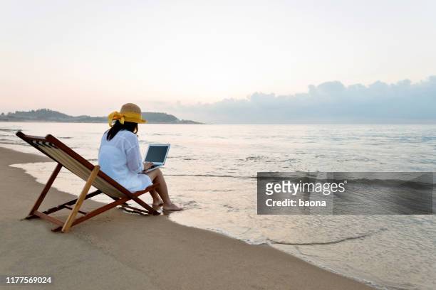 woman using laptop at the beach - time off work stock pictures, royalty-free photos & images