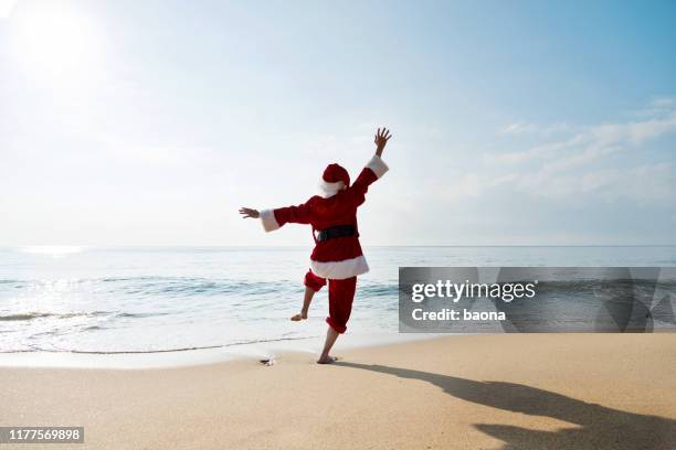 santa claus restant sur la plage de mer avec des bras soulevés - père noël photos et images de collection