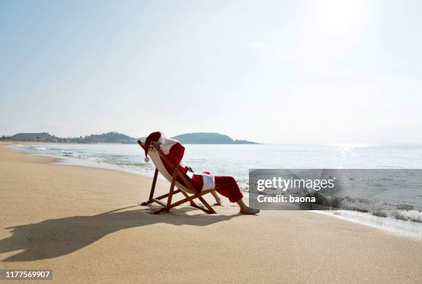 kerstman rustend op ligstoel op het strand - santa claus lying stockfoto's en -beelden