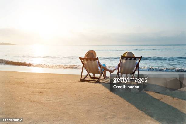 pareja sentada en la silla de cubierta en la playa - man on the beach relaxing in deckchair fotografías e imágenes de stock