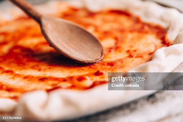 esparciendo salsa de tomate en la sartén de pizza - pizza fotografías e imágenes de stock