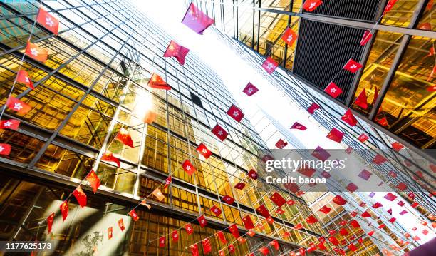 chinese and hong kong flags hanging between buildings - hong kong flag stock pictures, royalty-free photos & images