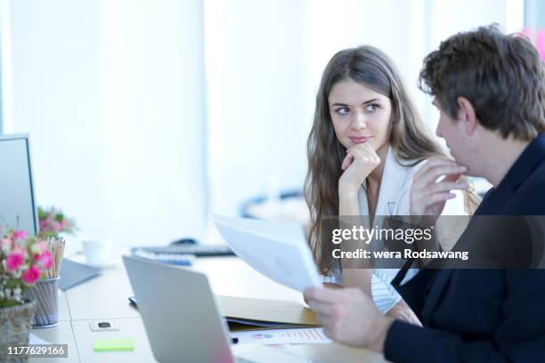 selective focus of attractive businesswoman looking at to the coworker sitting at place of work - kantoorromance stockfoto's en -beelden